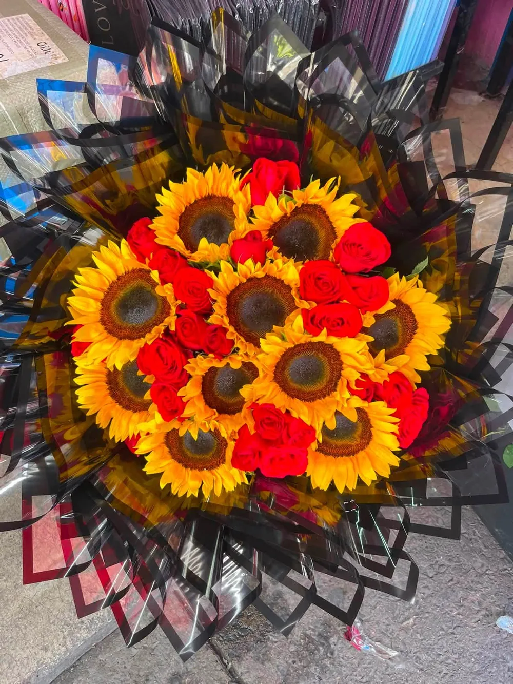 Girasoles y rosas rojas con envoltura negra de filo dorado en espiral