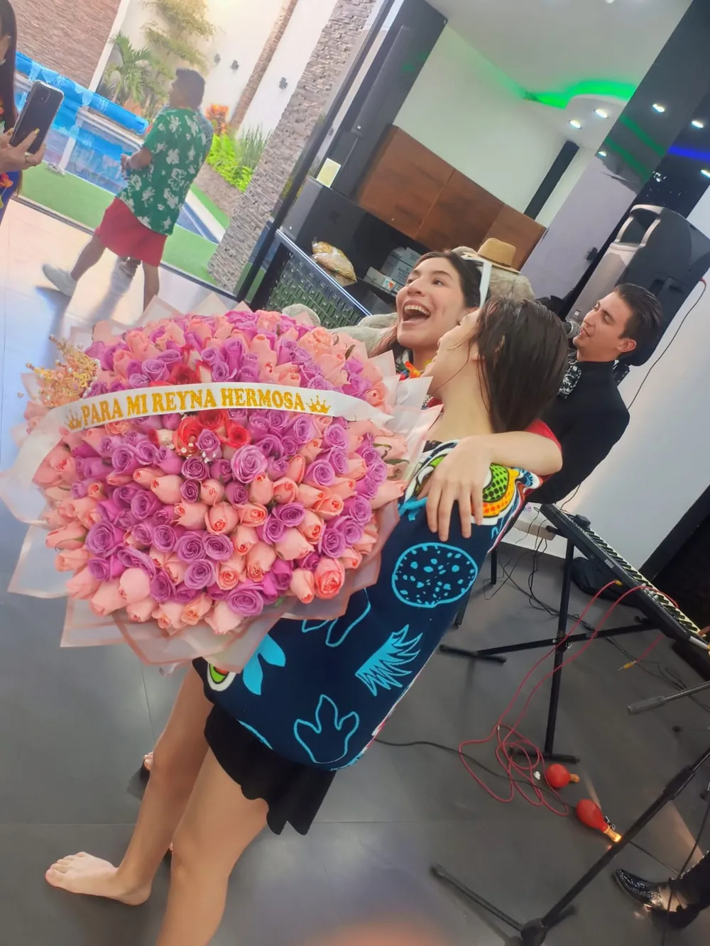 Mujer feliz abrazando a su pareja mientras recibe un ramo enorme de rosas rosadas