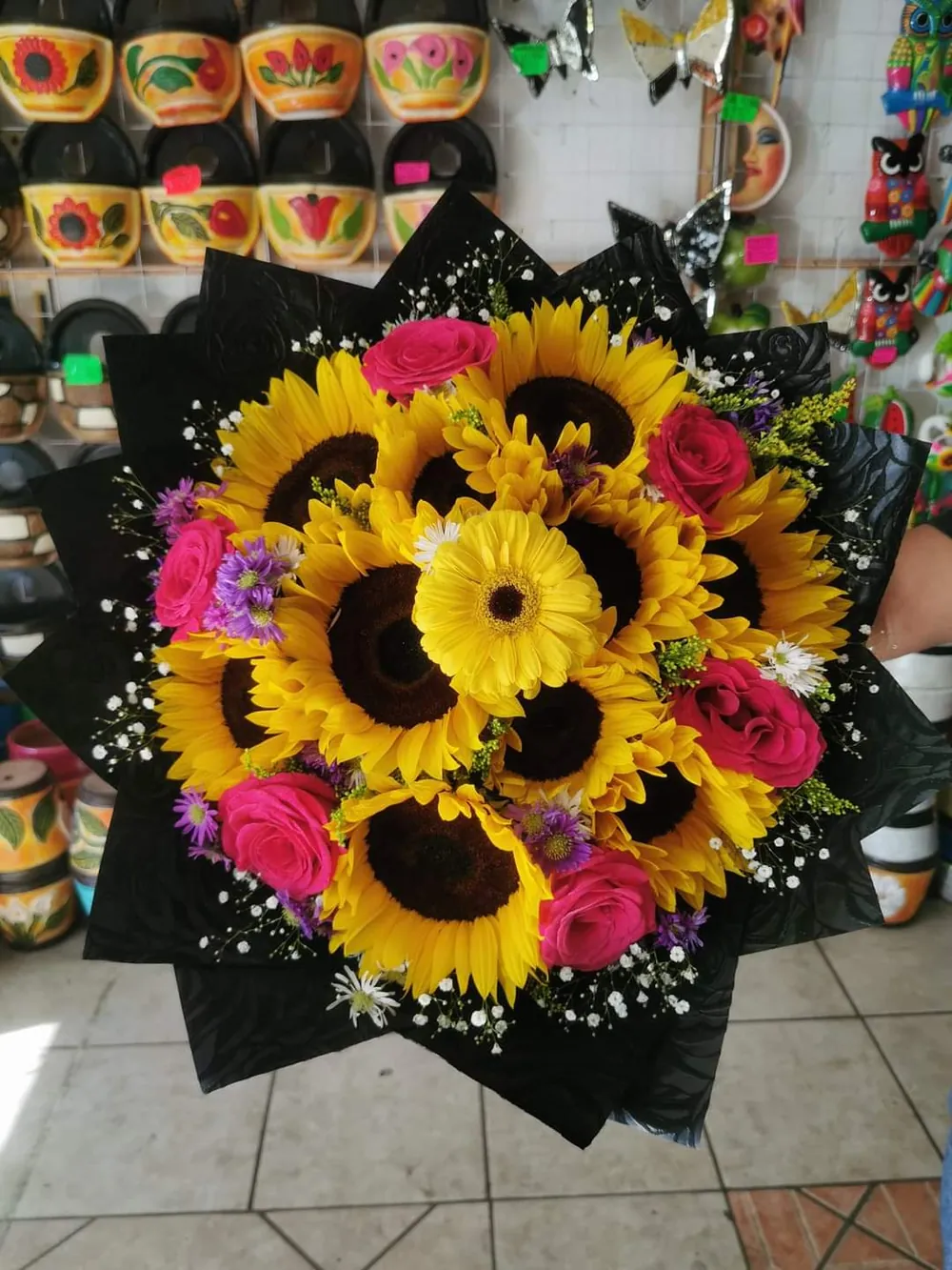 Ramo de girasoles con rosas fucsia y gypsophila sobre papel negro