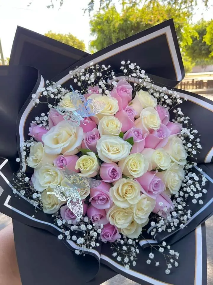 Ramo de rosas marfil y lila con nube de gypsophila sobre papel negro