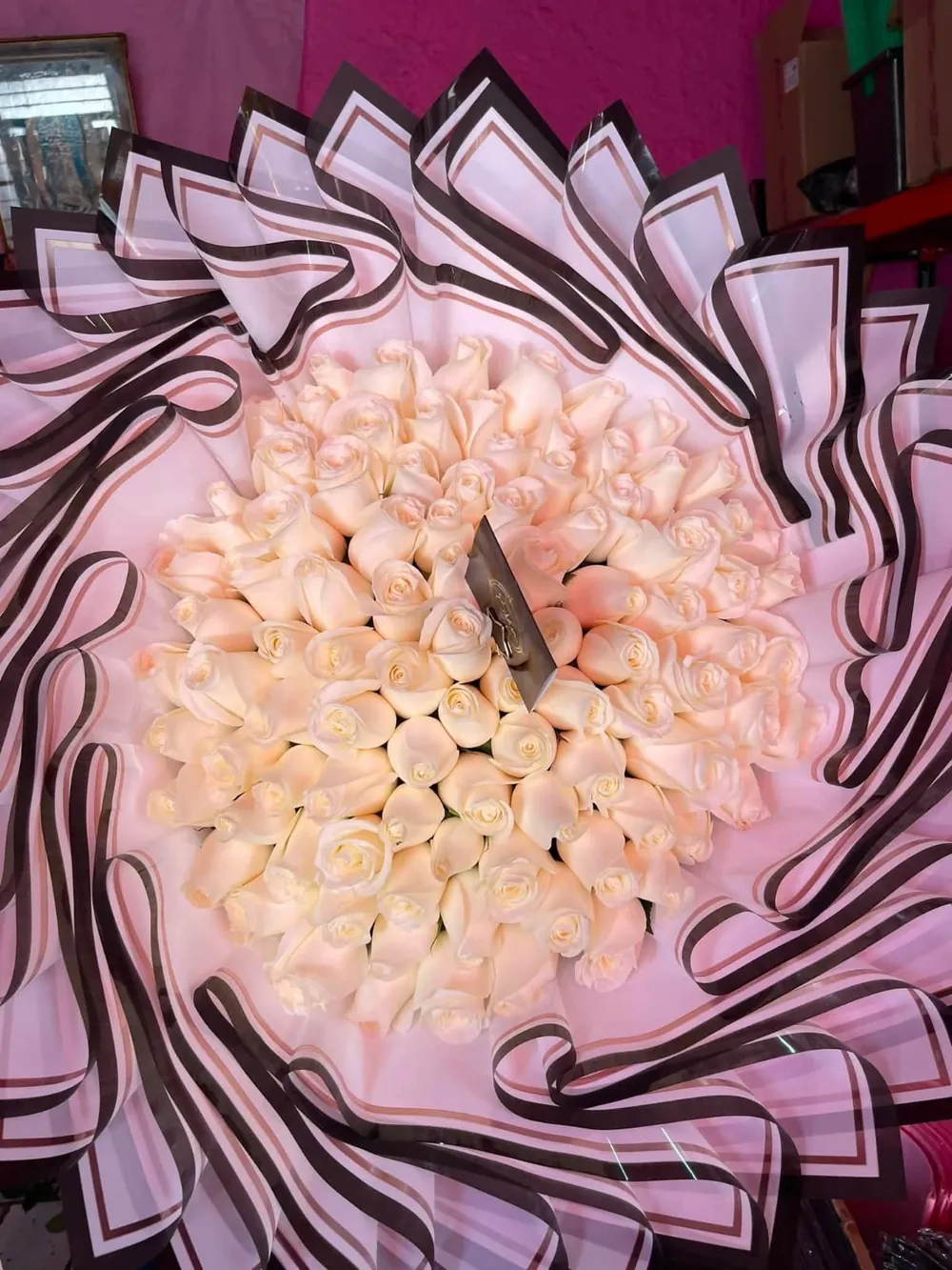 Ramo Champagne: rosas color crema en un remolino de papel con filo oscuro